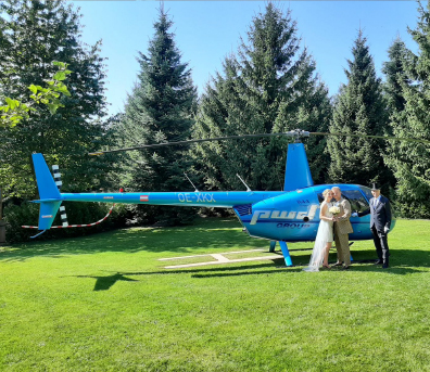 Brautpaar vor einem Hubschrauber auf dem Helikopter-Landeplatz